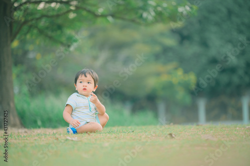 Boy among green grass on a summer day. A small child has fun in the fresh air. Baby explores the nature © grooveriderz