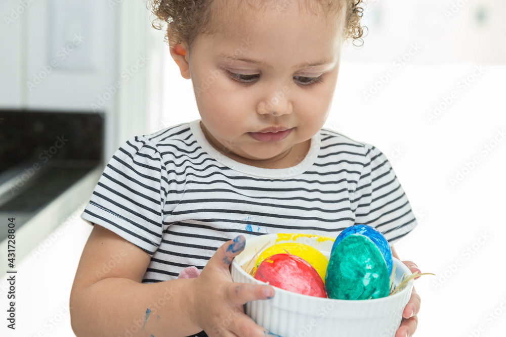 Fototapeta premium Child being very careful not to drop a basket with Easter eggs.