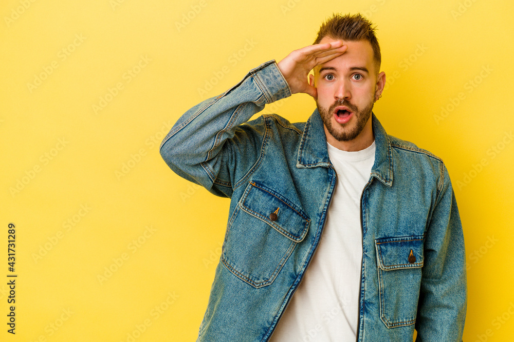 Young tattooed caucasian man isolated on yellow background looking far away keeping hand on forehead. Young tattooed caucasian man isolated on yellow background looking far away keeping hand on forehead.