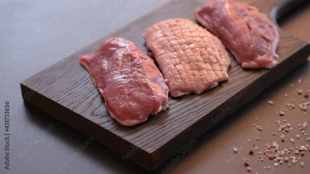 Raw duck breast with herbs and spices on a dark concrete background. Raw meat prepared for baking Raw duck breast with herbs and spices on a dark concrete background. Raw meat prepared for baking