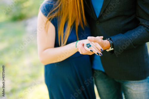 Man in a jacket holds the hand of woman in a long dress with a blue ring on her finger and a beautiful manicure. Close-up shot of hands