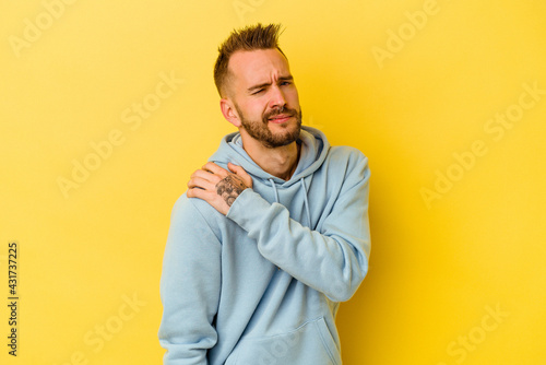 Young tattooed caucasian man isolated on yellow background having a shoulder pain.
