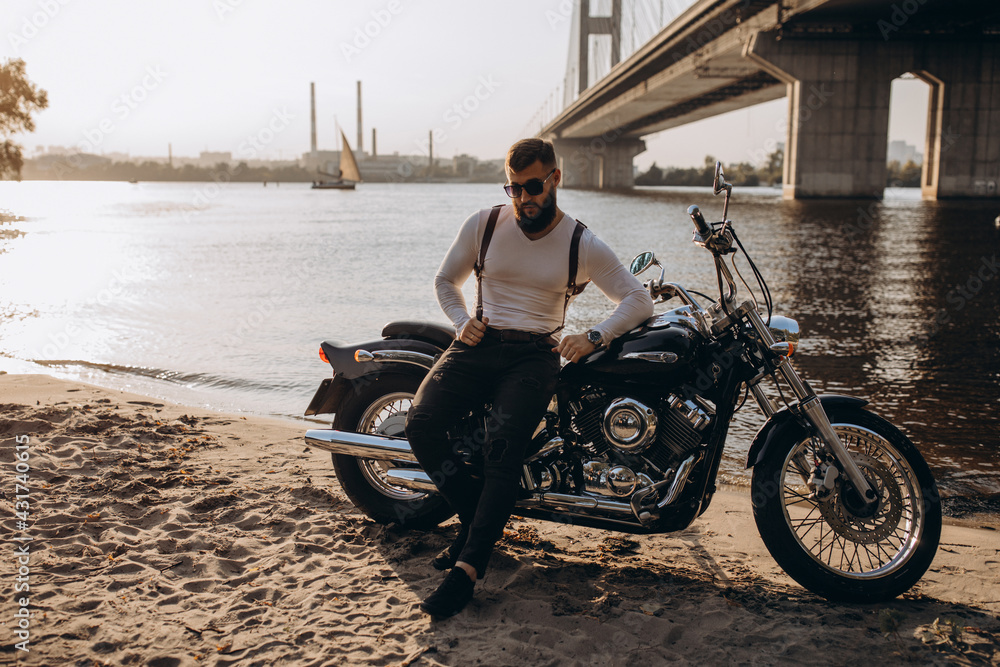 Naklejka premium The biker is resting on the river bank. Evening photo session.