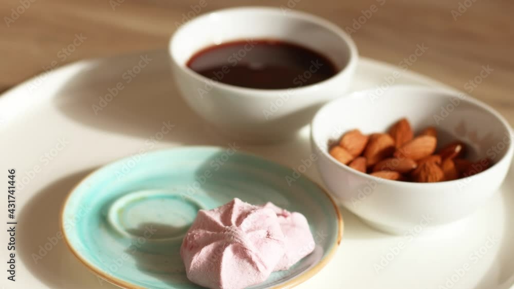 Closeup cup of black coffee with marshmallow desserts on a wooden table. Delicious puffed blueberry marshmallow on saucer Closeup cup of black coffee with marshmallow desserts on a wooden table. Delicious puffed blueberry marshmallow on saucer