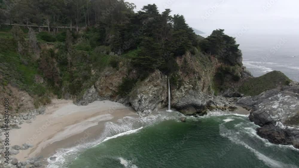 Aerial Shot Of Mcway Falls From Rocky Cliff At Beach, Drone Descending Forward Over Waves Splashing On Shore - Big Sur, California Aerial Shot Of Mcway Falls From Rocky Cliff At Beach, Drone Descending Forward Over Waves Splashing On Shore - Big Sur, California