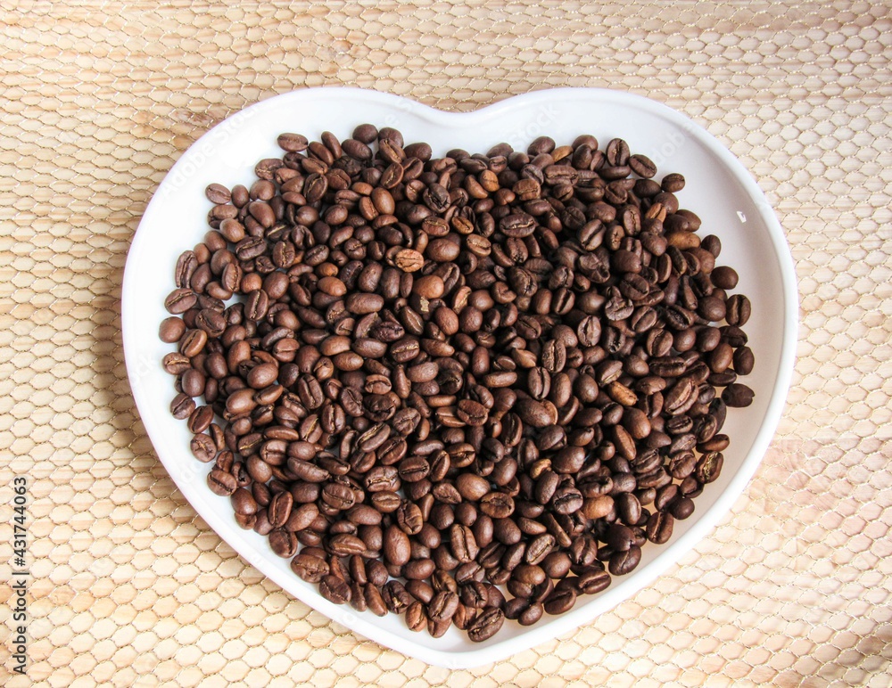 coffee beans on a white heart-shaped plate coffee beans on a white heart-shaped plate