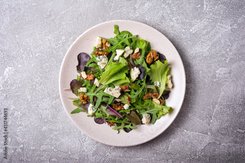 Healthy vegetarian salad with mix of fresh green leaves, blue cheese and walnuts