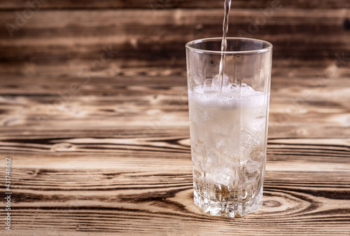 fresh seltzer water is poured into a glass with ice