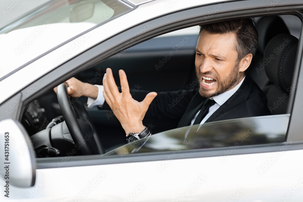 Expressive middle-aged businessman screaming while driving car
