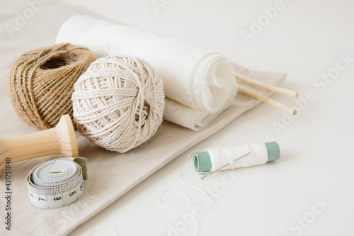 Accessories for sewing and handicraft: woolen threads, fabric cuts, needle and measuring tape. Sewing and needlework concept.