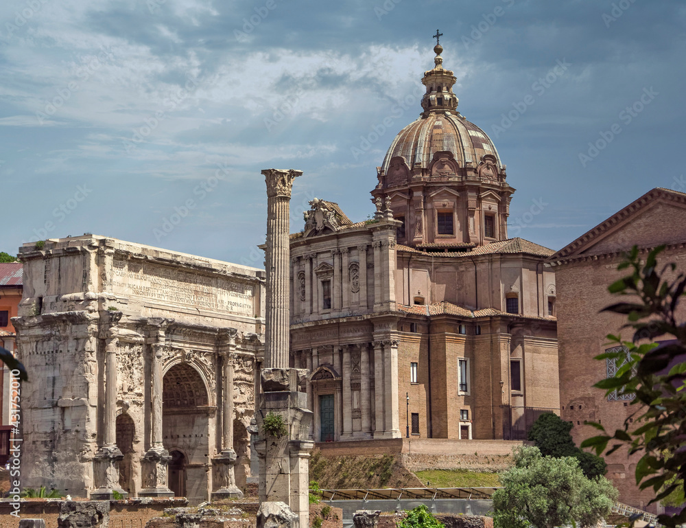 Rome Italy, trionfal arch of Septimus Severus Caesar and Santa Martina church under an impressive sky with sun rays
