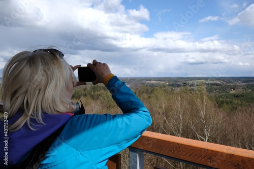 Woman in blue jacket is taking photo from observation tower on  Siemierzycka Mount, Bytowskie Lake District, Kashubia, Poland photo