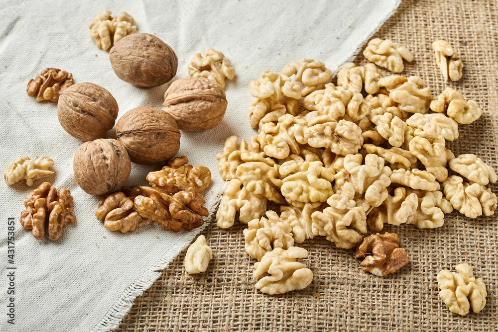 peeled and whole walnuts on a background of white and brown textured fabric peeled and whole walnuts on a background of white and brown textured fabric