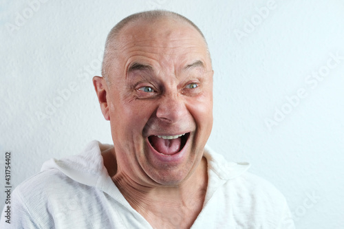 Photography close-up face of a middle-aged man, a senior in white looks, laughs cheerfully,