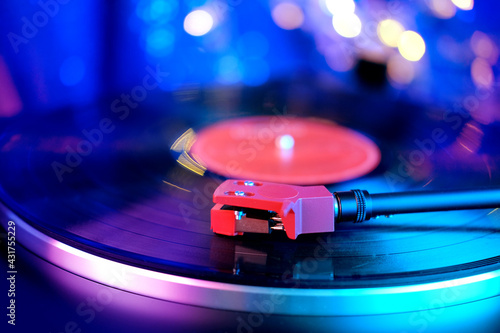 close-up of a pickup head on a vinyl record, color illumination, analogue retro music concept, audio experience, relaxation, musical enjoyment, vintage technology