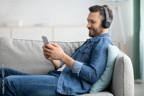 Positive bearded man with headset and mobile phone