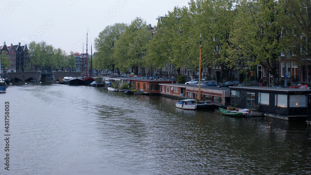 Amsterdam, Netherlands, April 2011: A cityscape of canal with reflections and home boats with typical Dutch buildings in springtime.