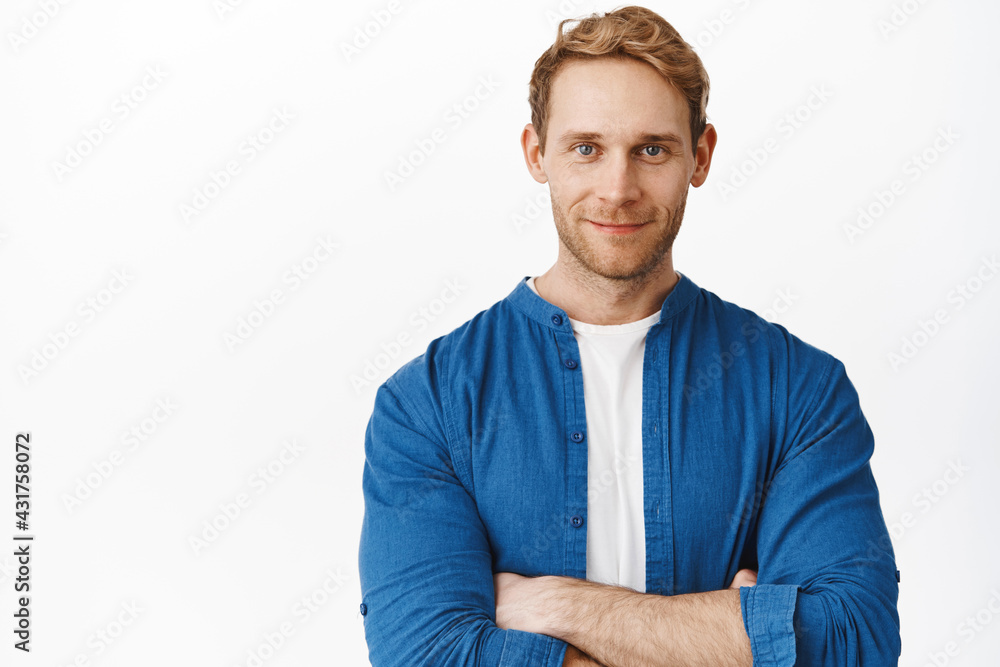 Close up of handsome professional man, cross arms on chest and looking confident at camera, smiling determined, standing against white background Close up of handsome professional man, cross arms on chest and looking confident at camera, smiling determined, standing against white background