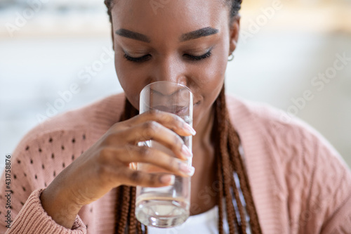 Refreshing Drink. Beautiful Young Black Lady Drinking Water From Glass At Home photo