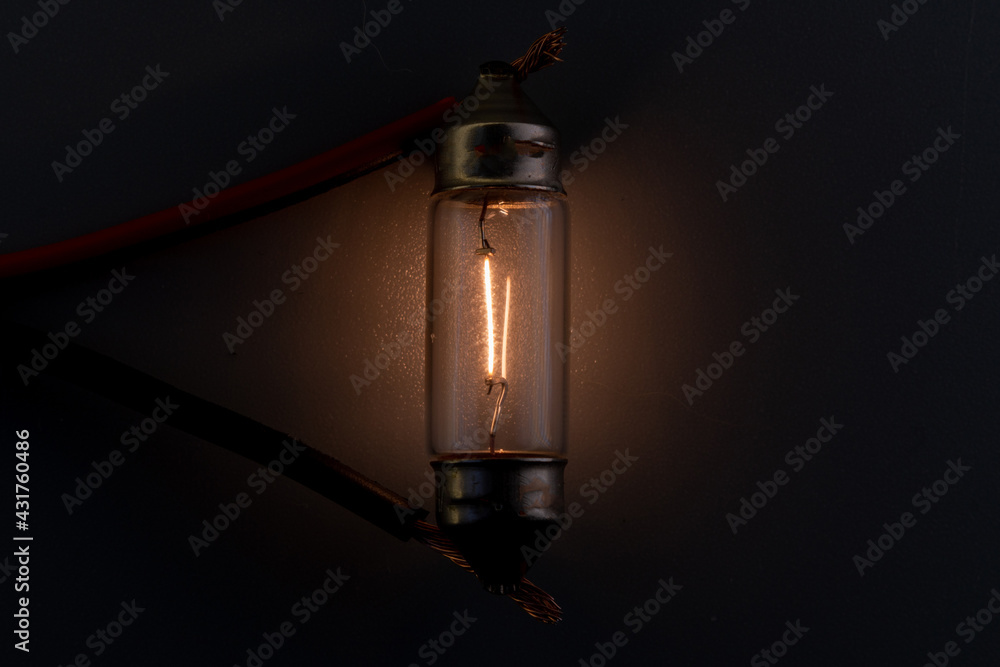 Car classic halogen bulb. Filament, glass and metal, high energy consumption. Black background. interior lighting. energized, working condition. Lights up