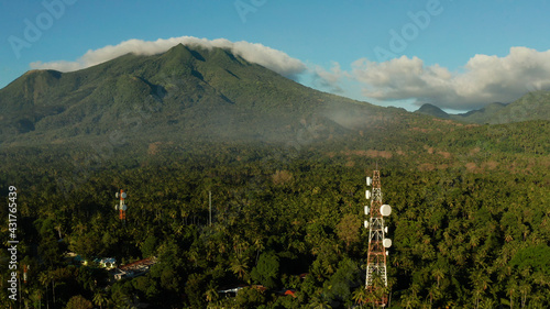 Antennas and microwaves link dishes of mobile phone network and TV transmitter on telecommunication towers with mountains and rainforest. Camiguin, Philippines