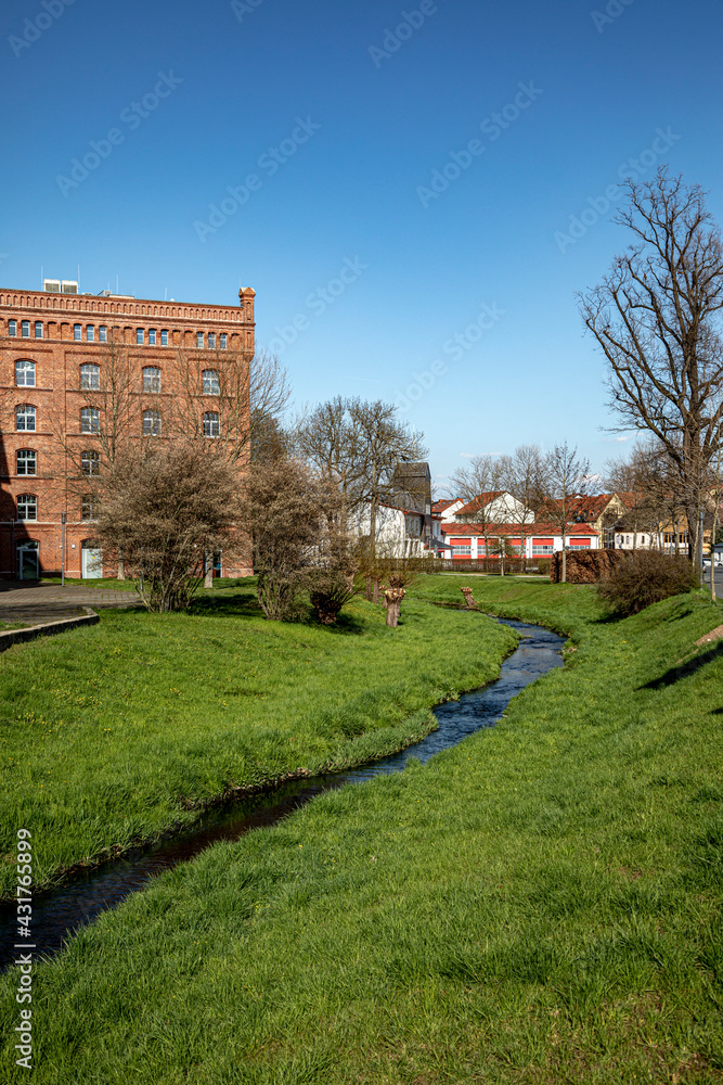 Old Renovated Industrial Building Made Of Bricks In Pößneck With The Brook In The Foreground, Thuringia, Germany, Europe