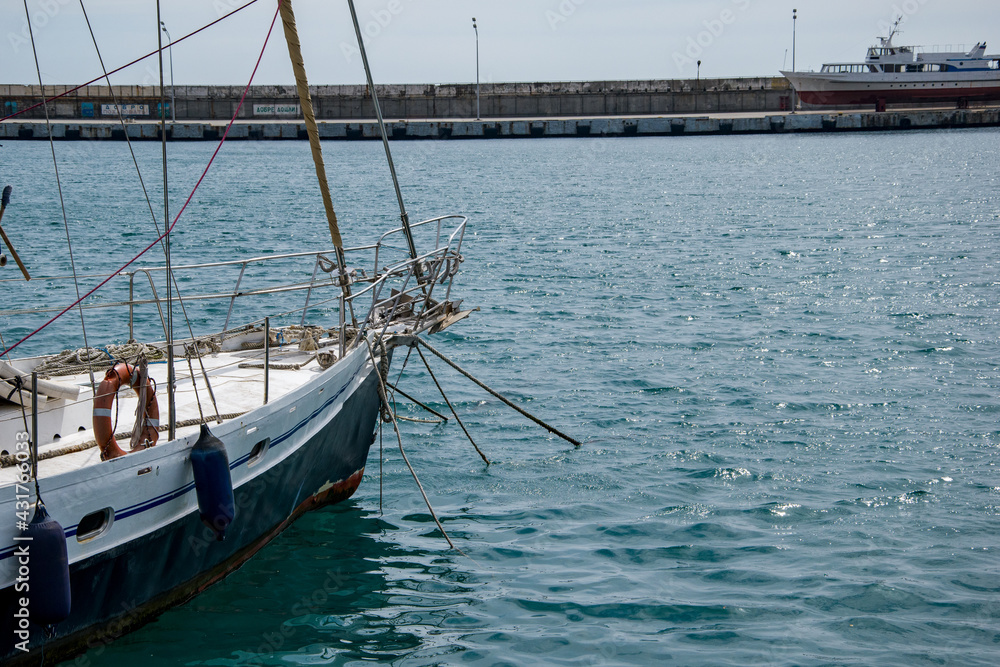 A sailing yacht is at anchor, close-up of the bow of the yacht. A pleasure yacht is moored at the pier