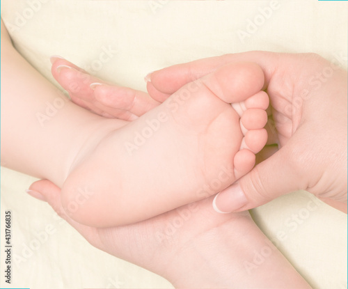Women s hands and baby leg close-up. The concept of of support  hope  love  bonding and care  hold on  motherhood  comforting. toning  soft focus