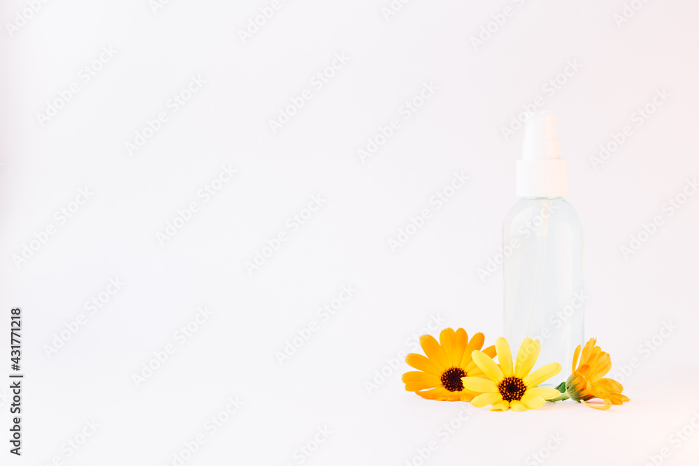 Container for natural cosmetics with calendula flowers on a white background with copy space. Aromatherapy. Spa and wellness Container for natural cosmetics with calendula flowers on a white background with copy space. Aromatherapy. Spa and wellness