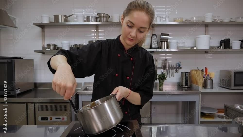 Close-up of a pastry chef in a uniform holding a spatula with liquid caramel. Close-up of a pastry chef in a uniform holding a spatula with liquid caramel.