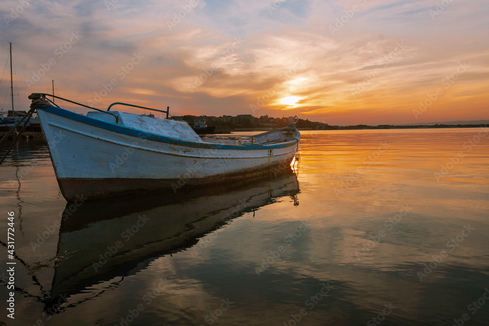 Naklejka premium Colorful sunset at the ocean with specular reflection with fisherman boat