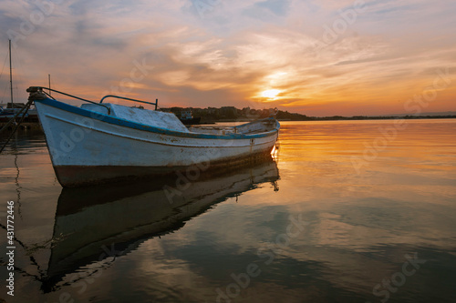 Colorful sunset at the ocean with specular reflection with fisherman boat