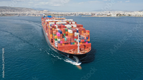 Aerial drone photo of truck size container cargo vessel cruising in deep blue Saronic gulf near commercial port of Piraeus, Attica, Greece