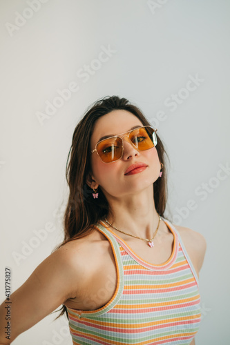 Portrait of attractive stylish woman in sunglasses with long brunette hair in studio.