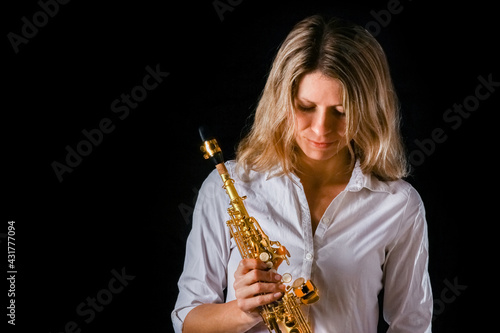 soprano saxophone in the hands of a girl on a black background photo