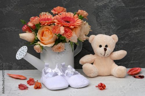 Babyschuhe mit Teddybär und Blumenstrauß. photo