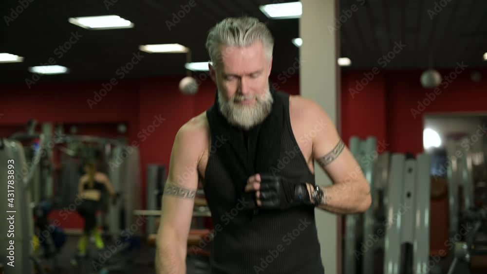 Gray haired man warming up before workout by running on a treadmill in the gym, close up Gray haired man warming up before workout by running on a treadmill in the gym, close up