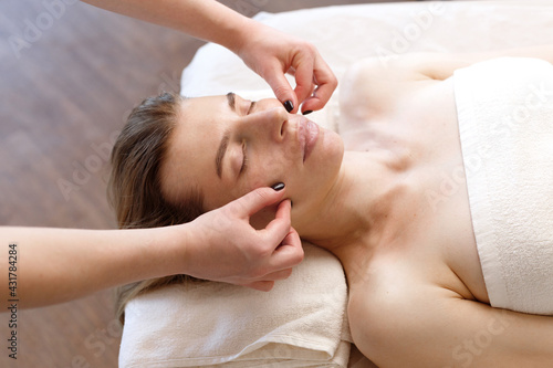 massage the face of a woman on the couch. masseur in the salon