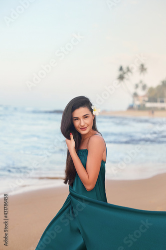 Beautiful smiling young woman in green dress on beach over sea and blue sky background. Summer  vacation  travel