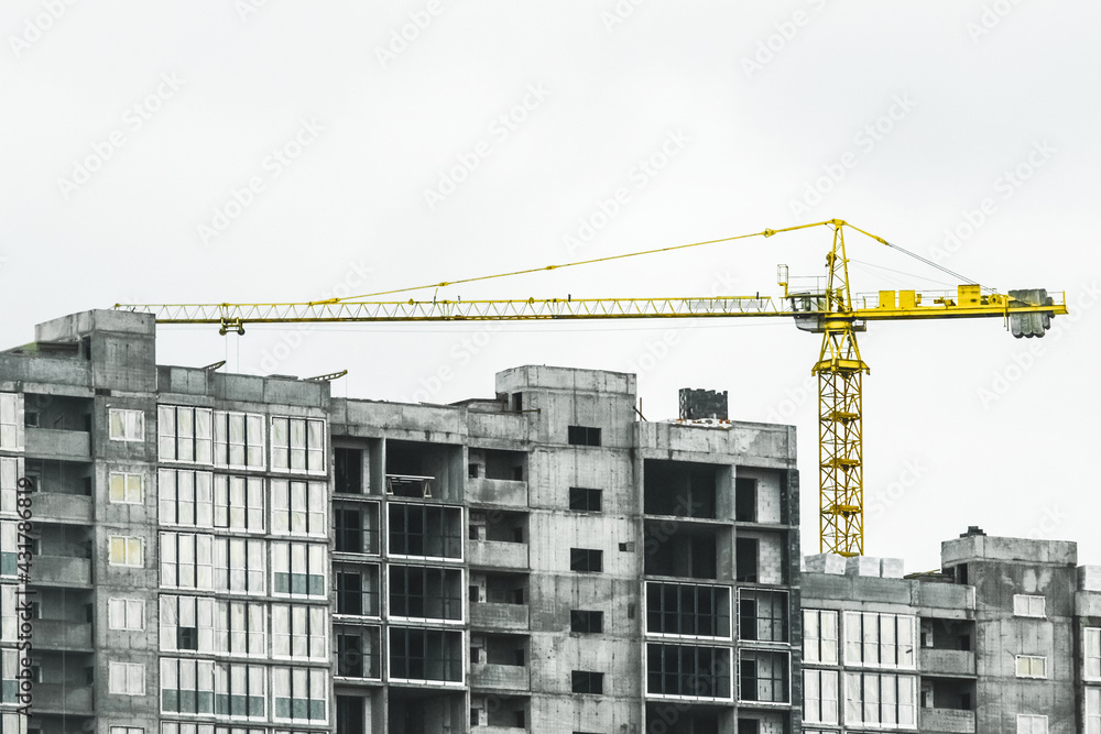 Tower yellow construction crane builds new concrete and cement city building on construction site Tower yellow construction crane builds new concrete and cement city building on construction site