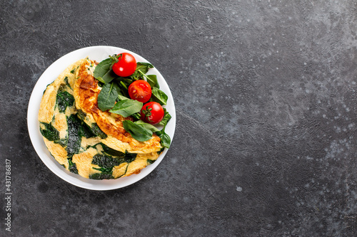 Frittata made of eggs, cheese and spinach salad. Frittata - italian omelet on a plate on a gray background. Ketogenic, keto food, menu recipe place for text, top view