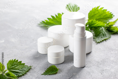 Natural spa, herbal cosmetics. Nettle lotion, shampoo and cream in a bottle and nettles leaves. Medicinal herb for health and beauty, skin care and hair treatment