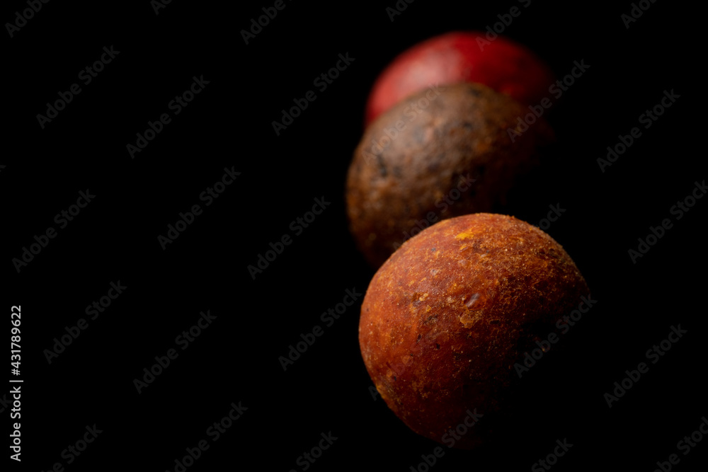 Protein balls for fishing carps of different colors on a black background. - obrazy, fototapety, plakaty 