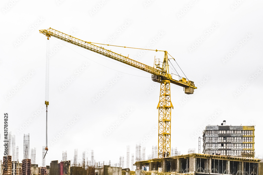 Belarus, Minsk - March 06, 2020: Industrial tower crane on a background of gray sky and an unfinished city building at a construction site Belarus, Minsk - March 06, 2020: Industrial tower crane on a background of gray sky and an unfinished city building at a construction site