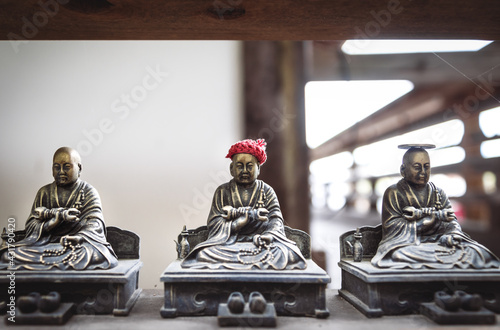 Small bronze buddhist statues with coin and hat offerings in Daisho-in temple in Miyajima, Hiroshima, Japan photo