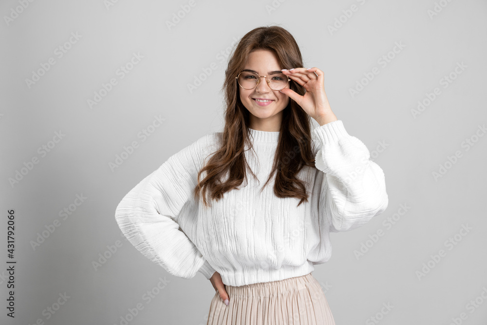 Beautiful, stylish girl correct eyeglasses on a gray background. Young girl posing on the background of an empty wall.