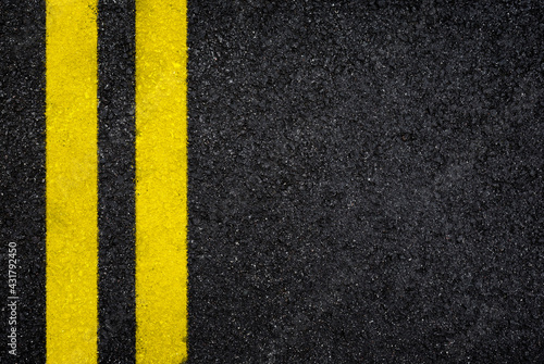 Top view of dark wet asphalt road with double yellow line. High resolution full frame textured background of black asphalt, viewed from above. Copy space.