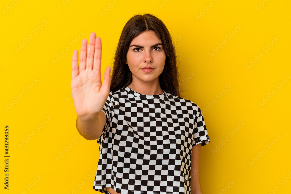 Young caucasian woman isolated on yellow background standing with outstretched hand showing stop sign, preventing you. Young caucasian woman isolated on yellow background standing with outstretched hand showing stop sign, preventing you.