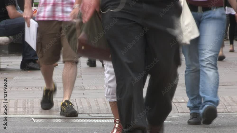 Anonymous shoppers cross the road carrying bags of purchases Anonymous shoppers cross the road carrying bags of purchases