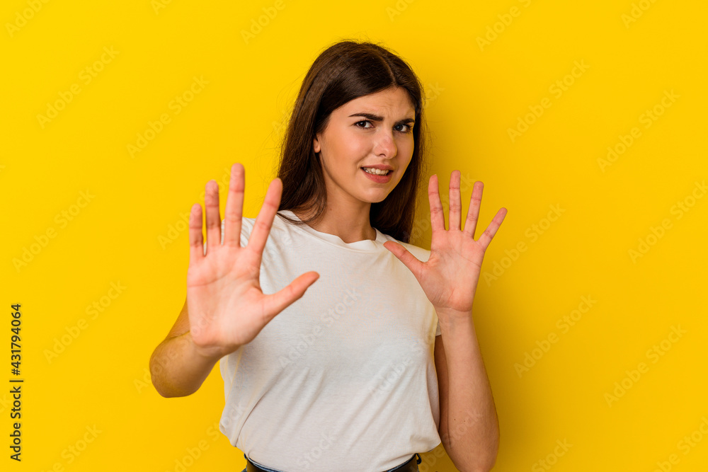 Young caucasian woman isolated on yellow background rejecting someone showing a gesture of disgust. Young caucasian woman isolated on yellow background rejecting someone showing a gesture of disgust.